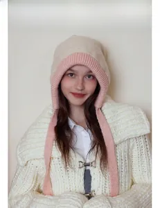 Detail of beige and pink knit balaclava hat with ear flaps and long ties