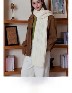 Detail of white chunky cable knit scarf showing soft wool texture and braided pattern