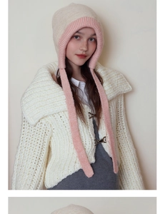 Close-up detail of soft knit texture and metal horn button on winter hat and cardigan