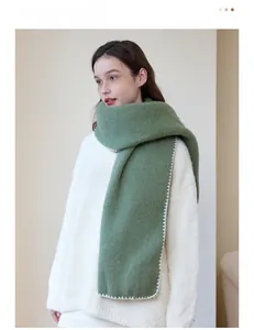 Detail of green knit scarf with white stitched edges and thick warm texture for winter