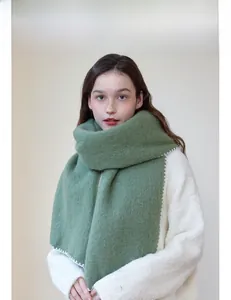 Detail of green knit scarf with thick white blanket stitch edges for winter warmth