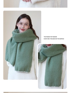 Detail of green thick plush scarf with white overlock stitching and soft texture