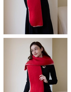 Detail of red winter scarf featuring white wavy stitched edges and soft wool texture