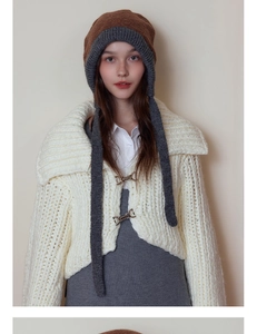 Detail of bicolor knitted ear-flapped hat with long tassels and thick wool texture