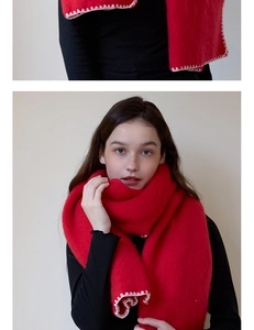 Macro shot of red knit scarf with white edge stitching detail on a model