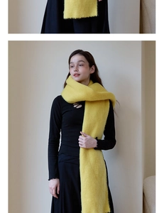 Detail of yellow thickened scarf with black contrast stitching and soft plush texture
