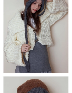 Detail of chunky knit texture and metallic D-ring buckle on vintage cream cardigan