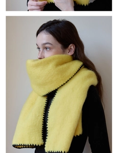 Close-up of thick yellow wool scarf featuring distinctive black wave edge lock stitching