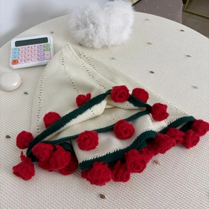 Detail of crochet rose blanket with red flowers and green scalloped edges on white knit fabric