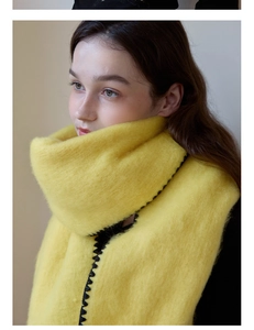 Detail of yellow thick mohair scarf with contrast black blanket stitch edge on model