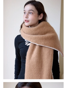 Close-up of thick camel knit scarf with white geometric edge stitching and soft texture