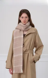 Gros plan d'une écharpe en maille à carreaux beige avec texture brossée sur un trench