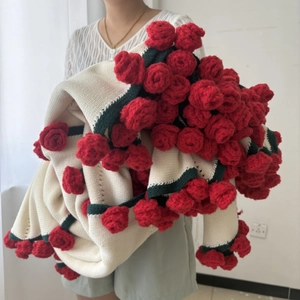 Detail of handmade knitted rose blanket featuring 3D floral texture and cream base fabric