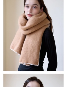 Close-up of camel knit scarf featuring thick warm fabric and white wavy stitched edges