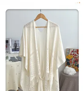 Detailed view of bohemian crochet hollow pattern and long tassels on a beige shawl