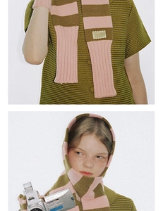 Gros plan sur une écharpe en maille rayée rose et verte avec écusson et gants assortis