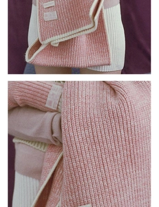 Detailansicht eines dicken rosa Strickschals mit weißen Rippkanten und weicher Textur