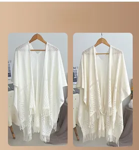 Close-up of beige knit cardigan showing geometric cutout patterns and long fringe details
