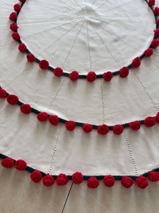 Close-up of handmade knit blanket featuring 3D red roses and green ribbon details