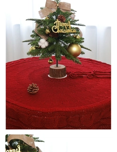 Detail of red cable knit Christmas tree skirt with textured pattern and festive ribbon