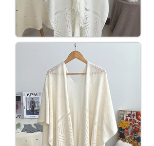 Detailed knit pattern of beige hollow-out tassel shawl on a wooden hanger