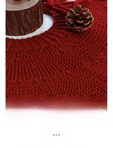 Detailed knit texture of a deep red acrylic Christmas tree skirt in a cozy rustic setting