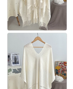 Detail of bohemian knit shawl with geometric cutout patterns and long fringe accents