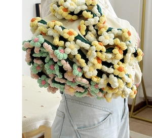 Detail of colorful 3D crochet flowers on a handmade cream-white knit floral blanket