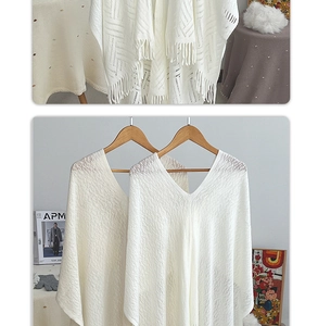 Close-up of white hollow knit shawl featuring V-neck and long elegant fringe tassels