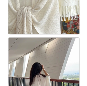 Detail of white hollow knit shawl with tassel fringe and textured diamond pattern