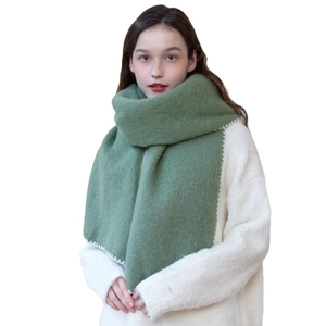 Olive green warm winter scarf with white scalloped stitching on white knitted sweater