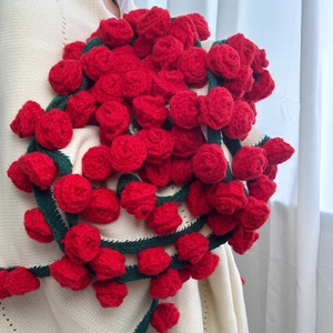 Close-up of handmade crochet rose scarf with 3D red flowers and green leaves detail