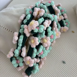 Handmade crochet floral blanket featuring pink and yellow roses with green knit leaves