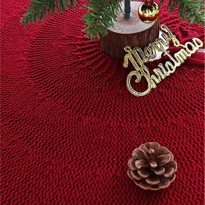 Classic red knitted Christmas tree skirt with festive pine cones and holiday decorations