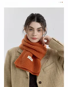 Detail of orange ribbed knit scarf showing texture and small white woven label accent