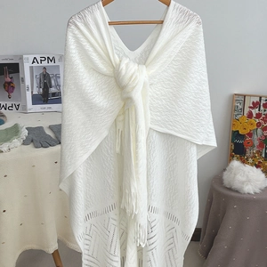 White knit poncho with V-neck, geometric hollow patterns and stylish tassel hem detailing