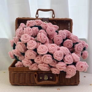 Handmade crochet pink rose bouquet in vintage woven suitcase on a bright table