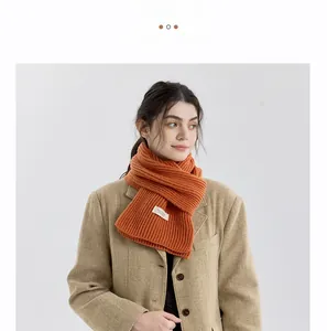 Detail of orange cashmere-like knitted scarf with white label on khaki coat