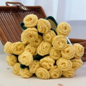 Handmade crochet yellow rose bouquet with green leaves in a rustic brown woven basket