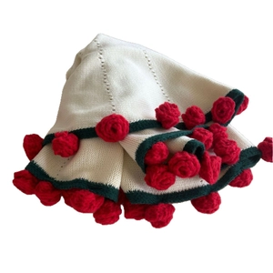 Handmade crochet blanket featuring red rose floral accents and white knit texture