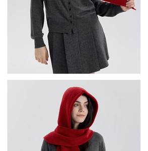 Detail of dark grey knit cardigan paired with a vibrant red hooded scarf for winter warmth