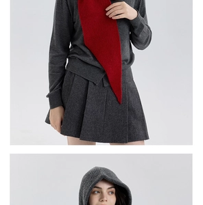 Detail of dark grey knitted hood and vibrant red scarf texture on winter outfit