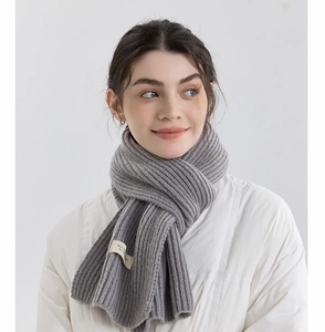 Detail of light grey ribbed knit scarf showing soft texture and decorative fabric label