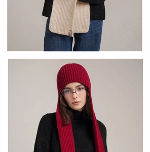 Detail view of red knitted hooded scarf with a leather logo tag and warm fleece texture