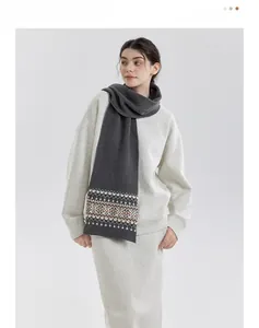 Detailed view of dark grey Fair Isle knit scarf with orange and white geometric patterns
