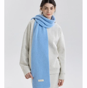 Close-up of light blue knit scarf featuring vertical stripes and a white decorative label