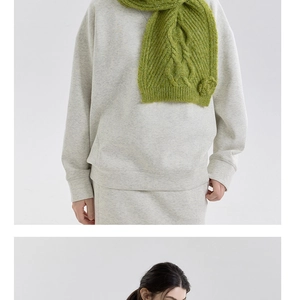 Close-up of green cable knit scarf with 3D floral details paired with a grey sweatshirt