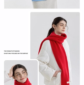 Detail view of chunky knit red cashmere-like scarf with minimalist white woven label