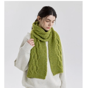 Macro detail of grass green knit scarf showing thick cable weave texture and warm wool yarn