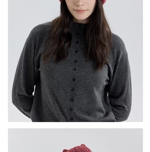 Détail d'un cardigan en maille gris foncé avec boutons et bonnet marron rouge